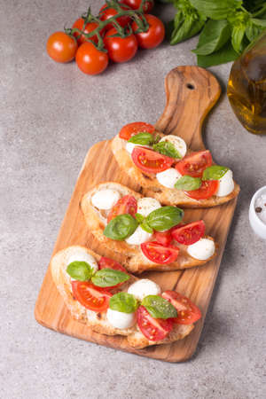 Tomato, basil and cheese fresh made caprese bruschetta. Italian tapas, antipasti with vegetables, herbs and oil on grilled ciabatta and baguette bread. Sandwich.の写真素材