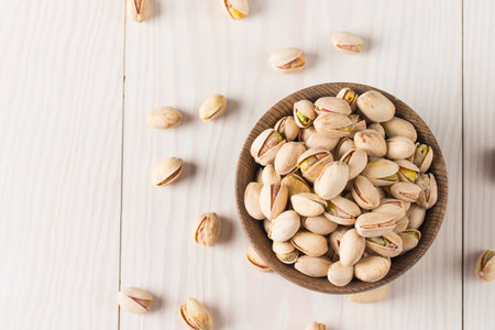 Pistachios in a wooden bowl on a white wooden backgroundの写真素材