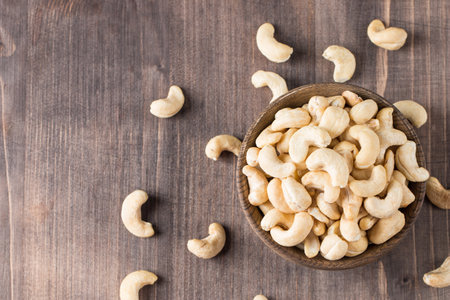 Cashew nuts in wooden bowl on wooden background. Top view.の写真素材