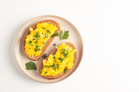 Scrambled eggs on toasted bread with parsley on white background
