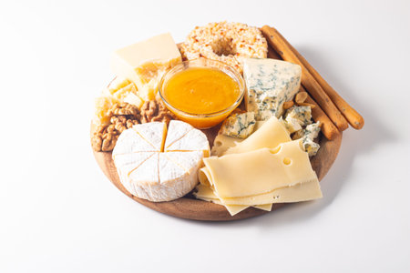 Cheese plate with honey, nuts and crackers on white background