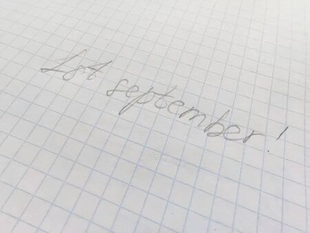 Handwritten inscription in pencil on the first of september on squared paper. Preparation for school, , the beginning of the school year, September 1, a sheet in a cageの写真素材