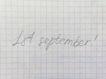 Handwritten inscription in pencil on the first of september on squared paper. Preparation for school, , the beginning of the school year, September 1, a sheet in a cageの写真素材