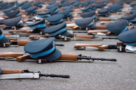 Military guns and caps lying on the concrete floor.