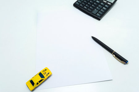 Black ballpoint pen, calculator and yellow car on blank paper form. Blank paper for car insurance paper.の写真素材