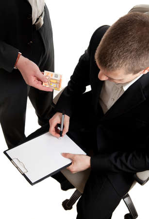 a young businessman being bribed while signing contractの写真素材