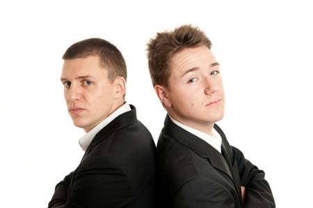 closeup of two young businessmen standing back on backの写真素材