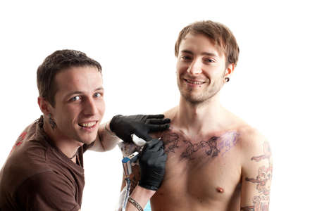 a tattoo artist and his customer during a tattoo session smiling into the cameraの写真素材