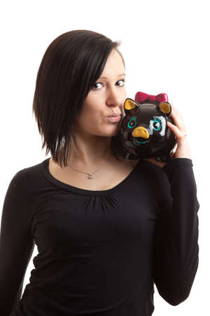a young woman kissing a piggy bank on her shoulder isolated on whiteの写真素材
