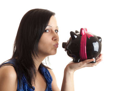 a young woman kissing a piggy bank isolated on whiteの写真素材