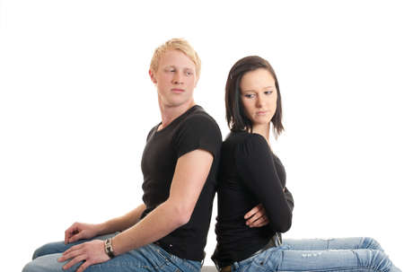 a young couple sitting back on back looking sadの写真素材