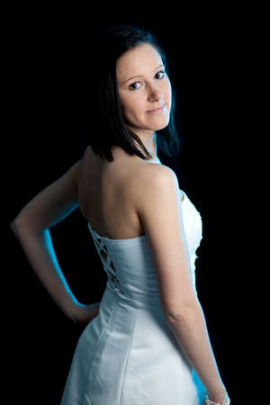 a young woman in a white dress looking backward over her shoulder lit by blue backlightの写真素材