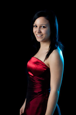 portrait of a young woman in a red dress lit by blue backlightの写真素材