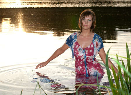 a young woman standing in the water reflections from the sun lightened up with flashの写真素材