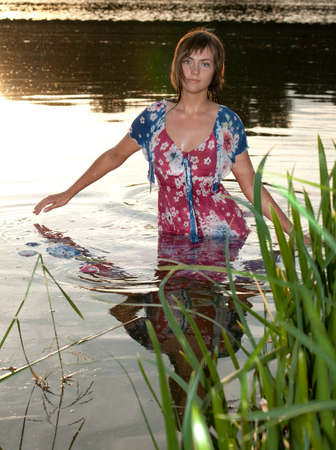 a young woman standing in the water reflections from the sun lightened up with flashの写真素材