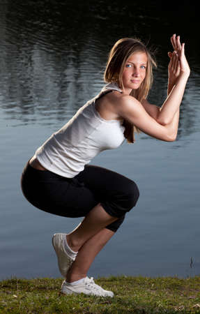 a young woman in a yoga stance in front of a lakeの写真素材