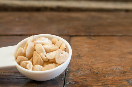A pile of cashew in the measuring tablespoon show on the left prepared to make bakery