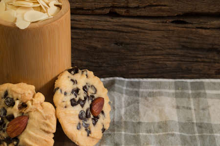 chocolate chip cookies put beside the almond in the bamboo cup on the handkerchief. ,on wooden background.の写真素材