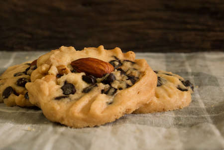 three chocolate chip cookies put on the handkerchief, on the wooden backgroundの写真素材