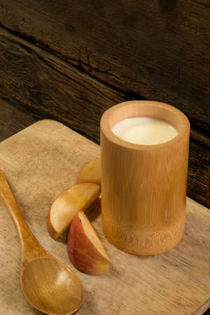 The diet breakfast - Piece of apple arranged around a bamboo cup of milk put on the flat plate,view from topの写真素材