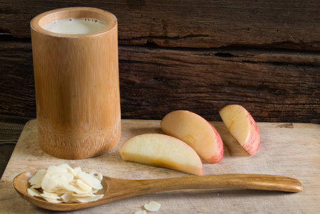 The diet breakfast -  a cup of soymilk on the wooden flaten plate  decorated with sliced almondの写真素材