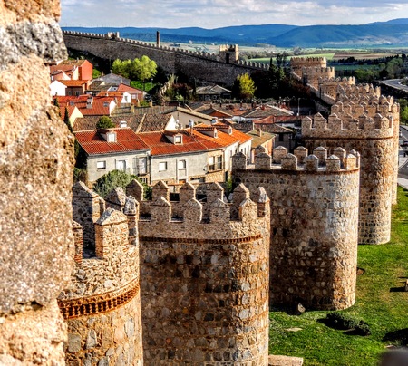 Wall Tower Bastion Avila Spain Made Yellow Stone Bricks with view of town and countryside with clouds and mountains in the backgroundの写真素材