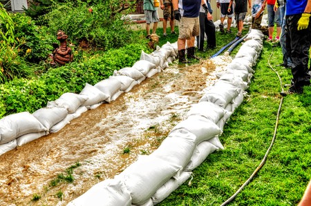 Neighborhood Flood, Volunteers devote themselves to prepare the sandbags to channel the water.の写真素材