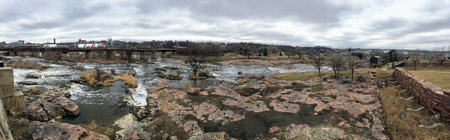 The Big Sioux River flows over rocks in Sioux Falls South Dakota with views of wildlife, ruins, park...