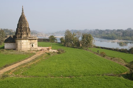 Old Hindu temple surrounded by lush green fields in Orchha Madhya Pradesh Indiaの写真素材