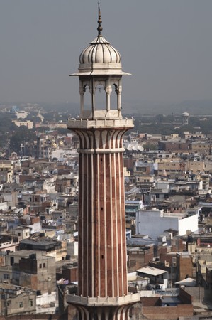 Standing tall against the surrounding houses a minaret of the Friday Mosque in Old Delhi Indiaの写真素材