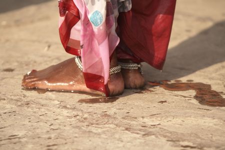 Feet of a woman in red and pink sari standing on ghats after bathing in the river. Varanasi Uttar Pradesh Indiaの写真素材