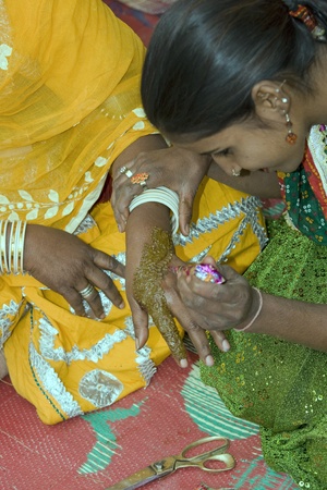 Haryana, India - February 3, 2008: Indian lady applying ornate henna hand painting to the hand of another Indian ladyのeditorial素材