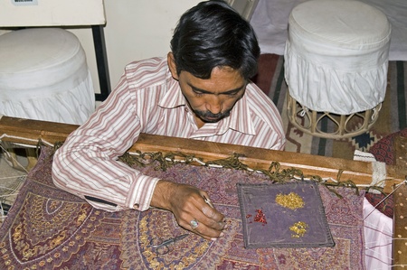 Jaipur, India - December 29, 2006: Craftsman sewing attaching sequins to a shawlのeditorial素材