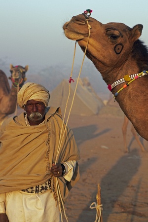Nagaur, Rajasthan, India - February 15, 2008: Indian man standing holding his camel at the Nagaur Cattle Fair, Rajasthan, Indiaのeditorial素材