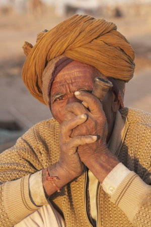 Nagaur, Rajasthan, India - February 15, 2008: Old Indian man in a turban smoking a pipe at the...