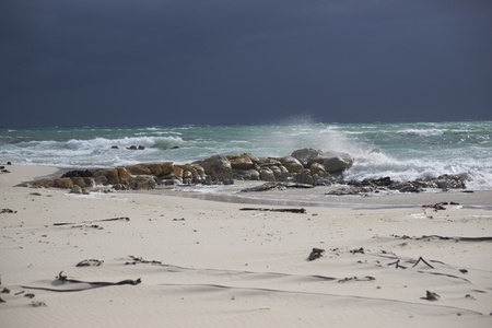 Dark clouds over a sunlit stormy sea and sandy beach on Cape Peninsula of South Africa の写真素材