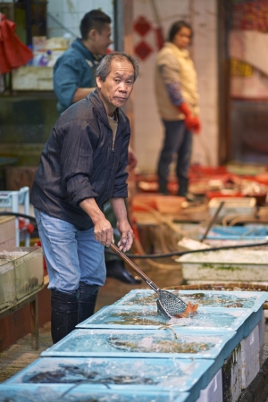Hong Kong - January 27, 2012: Man selling fish at an open air fish market in Kowloon, Hong Kongのeditorial素材