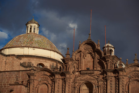 Colourfully tiled dome of the Iglesia de la Compania in the Plaza de Armas of Cusco in Peru. The dome is illuminated against dark storm clouds.の写真素材