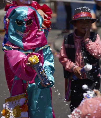ARICA, CHILE - JANUARY 23, 2016: Child in masked costume spraying foam at people during by the annual Carnaval Andino con la Fuerza del Sol in Arica, Chile.のeditorial素材
