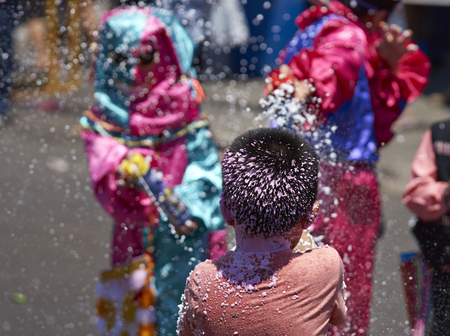 ARICA, CHILE - JANUARY 23, 2016: Child getting sprayed with foam by masked children at the annual Carnaval Andino con la Fuerza del Sol in Arica, Chile.のeditorial素材