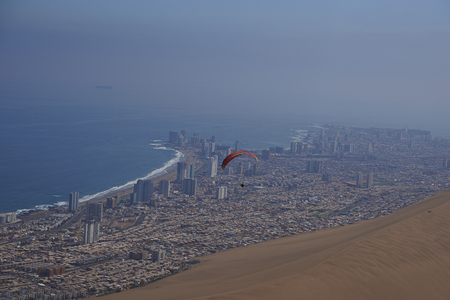 Iquique, Tarapaca Region, Chile - August 20, 2017: Paraglider over the coastal city of Iquique on the northern coast of Chile.の写真素材