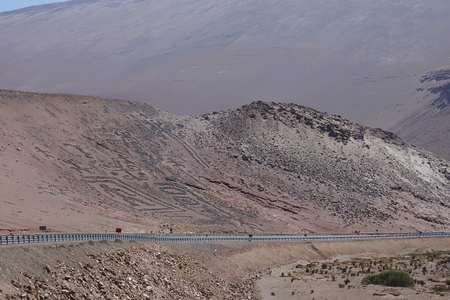 Petroglyphs, ancient form of rock art, on an arid hillside alongside the Pan American Highway in the Atacama Desert of northern Chile near Caleta Camerones.の写真素材