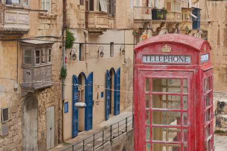 Valetta, Malta - June 6, 2023: Red telephone box amongst historic buildings in the city of Valetta in Maltaのeditorial素材