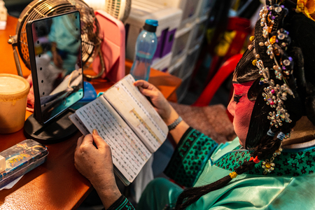Chinese opera artiste reading scripts at backstage before performanceのeditorial素材