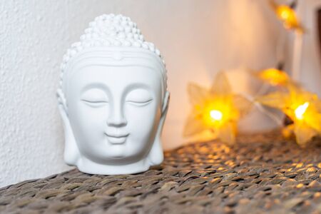 Miniature white buddha head & face. Illuminated background. Home decoration ornaments.の写真素材