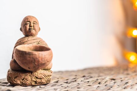 Miniature monk statue. Illuminated background. Home ornament decoration concept. Empty copy negative space for text.の写真素材