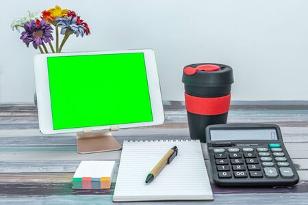 Office and school stationery supplies, reusable cup, mobile tablet with green screen. Business Objects Technology concept.の写真素材