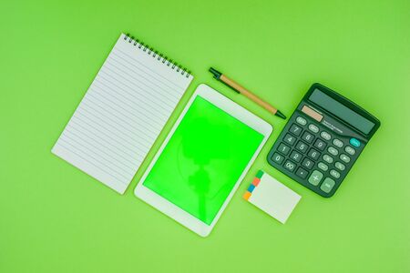 Green screen tablet, office school stationery on green background. Flat lay top down view. Business Objects Technology concept.の写真素材