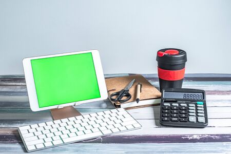 Office and school stationery supplies, reusable cup, keyboard and mobile tablet with green screen. Business Objects Technology concept.の写真素材