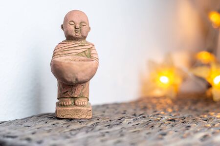 Miniature monk statue. Illuminated background. Home ornament decoration concept. Empty copy negative space for text.の写真素材